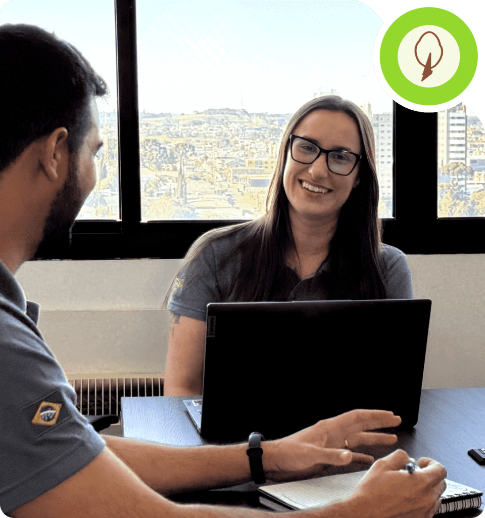 Mulher sorrindo em uma reunião de negócios. Logo da Álamo no canto superior direito.